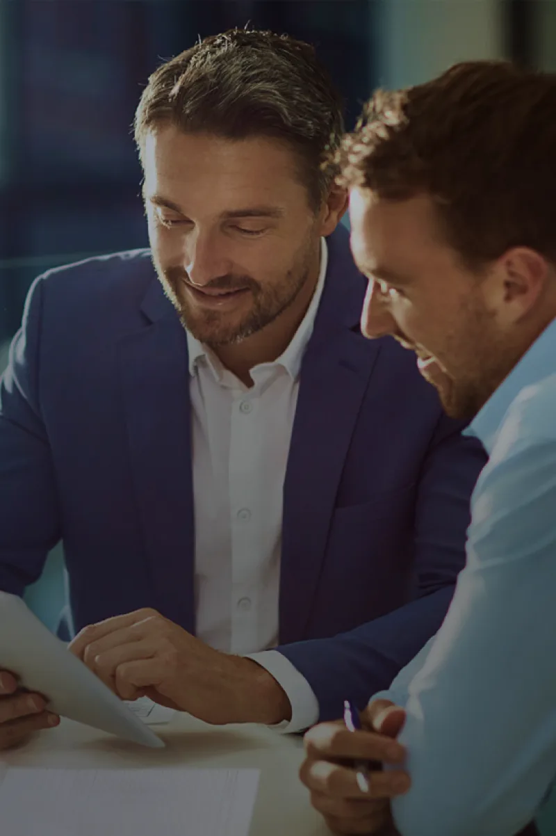 Two dealership managers reviewing training material on a tablet